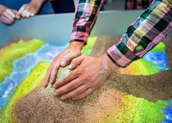 Aus Sand kann im Labor ein Höhenprofil aufgeschichtet werden. Ein Scanner erfasst es und projiziert farbcodierte Höhenlinien darauf. Mit Handbewegungen kann virtueller Regen ausgelöst werden. Bild: Damian Gorczany