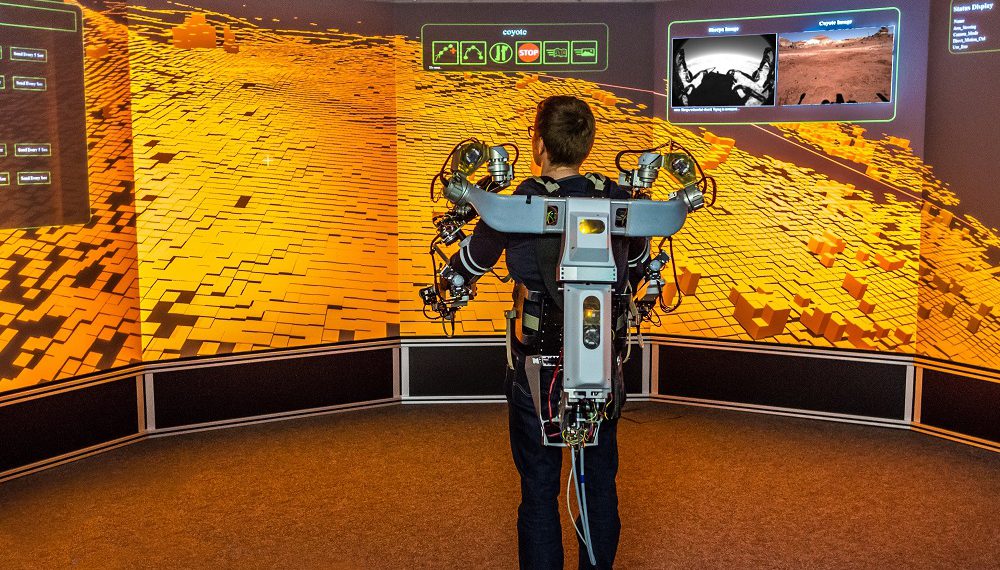 Ein Operator steuert mithilfe eines Oberkörper-Exoskeletts einen Roboter in Utah (USA) von einem virtuellen Leitstand am DFKI in Bremen.