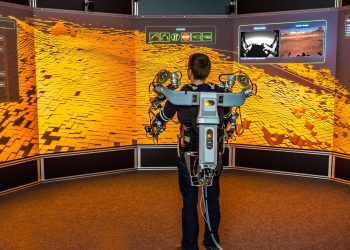 Ein Operator steuert mithilfe eines Oberkörper-Exoskeletts einen Roboter in Utah (USA) von einem virtuellen Leitstand am DFKI in Bremen.